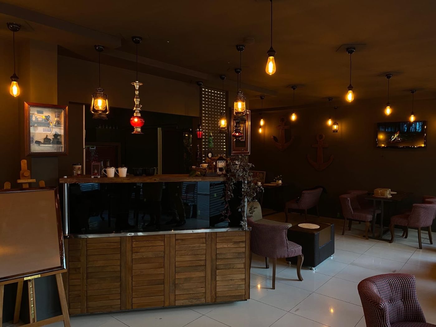 Le Bonjo'nun salonu: ahşap bar, asılı fenerler, kırmızı camlı lamba ve tavandan sarkan Edison ampuller.